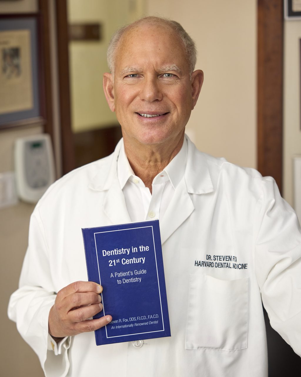 Dr. Steven Fox holding his book, Dentistry in the 21st Century